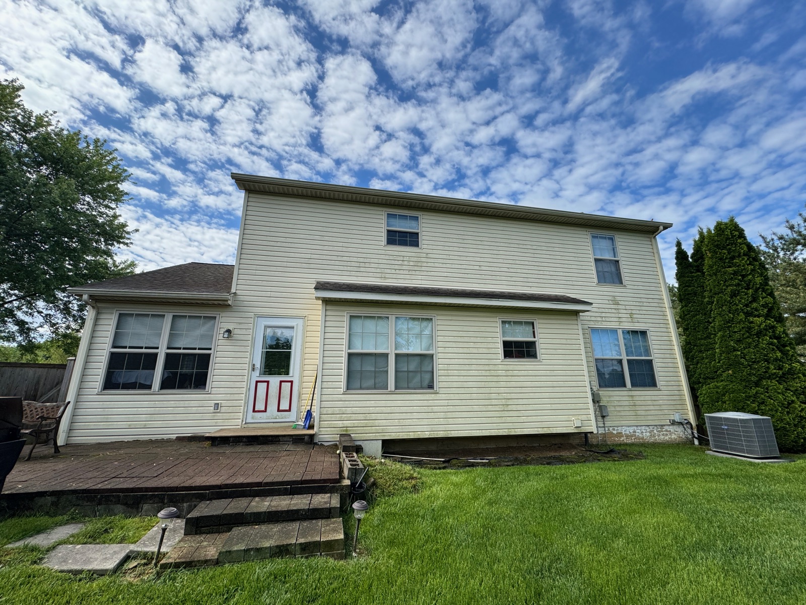 Rear of a two-story home with algae-streaked siding before soft washing